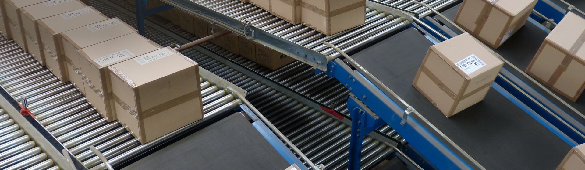 Rollbahnen mit Paketen in einem Lager Rollbahnen mit Paketen in einem Lager
