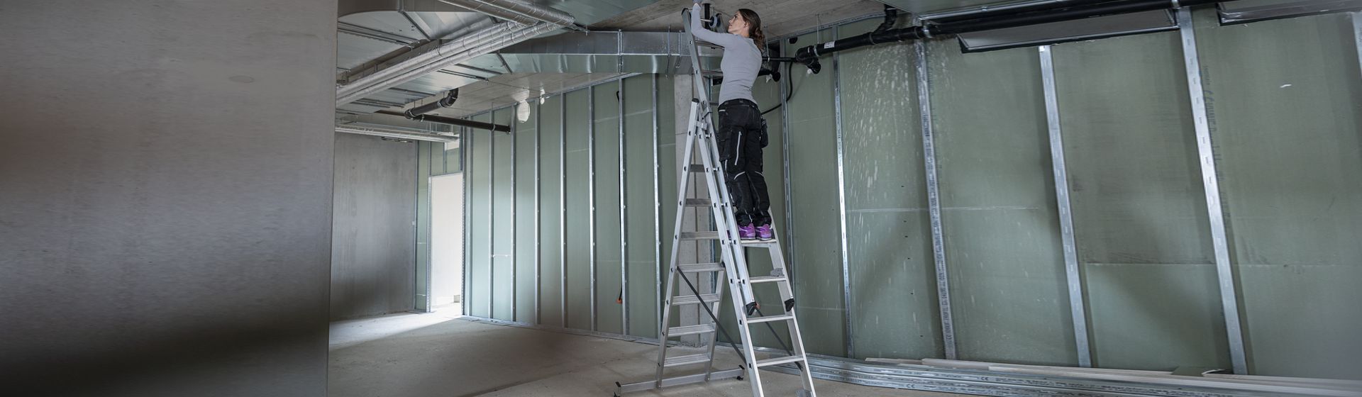 Handwerkerin auf einer Munk Günzburger Steigtechnik Mehrzweckleiter Handwerkerin auf einer Munk Günzburger Steigtechnik Mehrzweckleiter