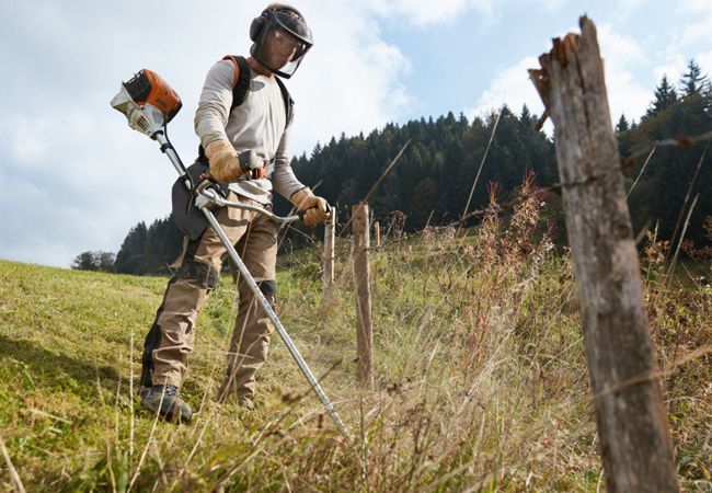 Mann mäht Wiese mit einer Stihl Motorsense