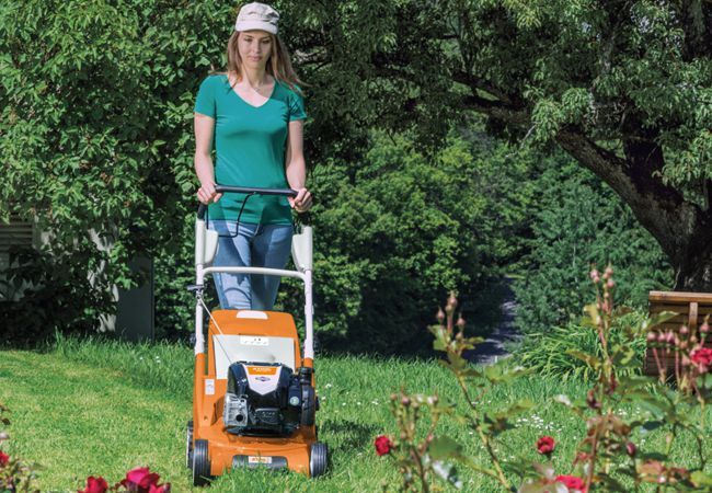 Frau mäht Rasen mit Stihl Rasenmäher