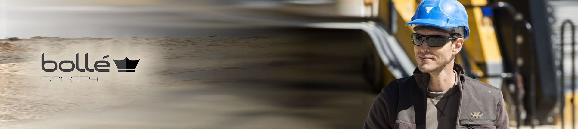 Handwerker mit blauem Schutzhelm und einer schwarzen Sonnen-Schutzbrille von Bollé Safety Handwerker mit blauem Schutzhelm und einer schwarzen Sonnen-Schutzbrille von Bollé Safety