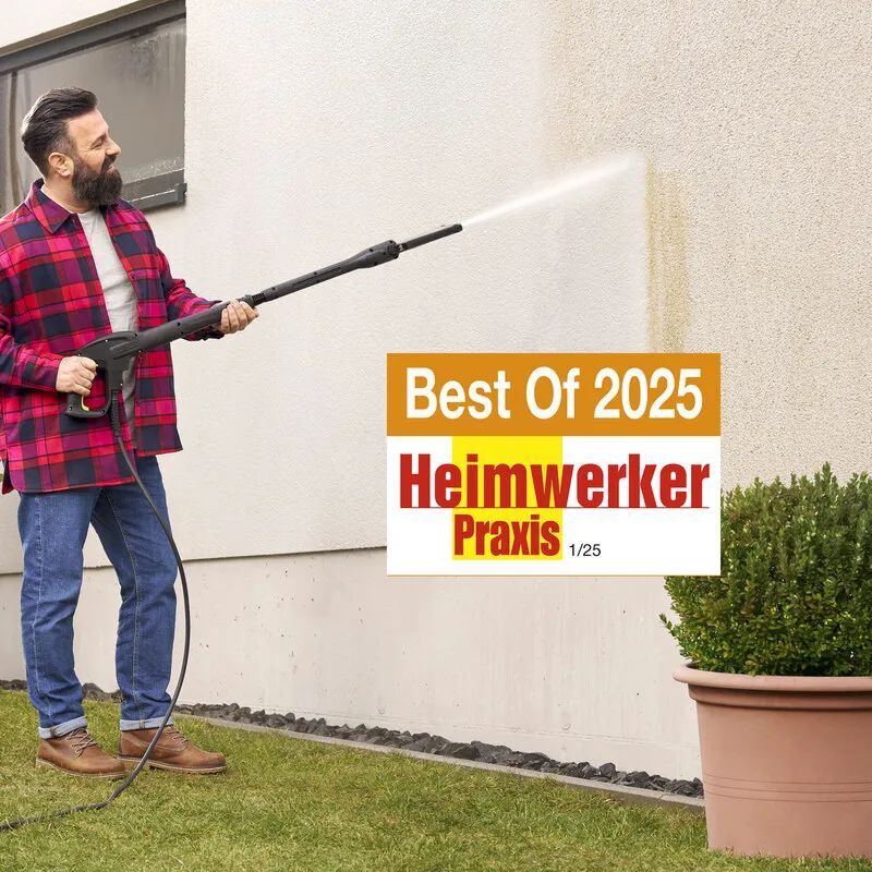 Kärcher Eco Booster Auszeichnung Best of Heimwerker Praxis 2025 Ein mit Jeans und Karohemd bekleideter Mann mit dunklem Bart und dunklen Kurzen Haaren steht auf einem Rasenstück und reinigt eine Hauswand mit einem Kärcher Eco Booster bild 2