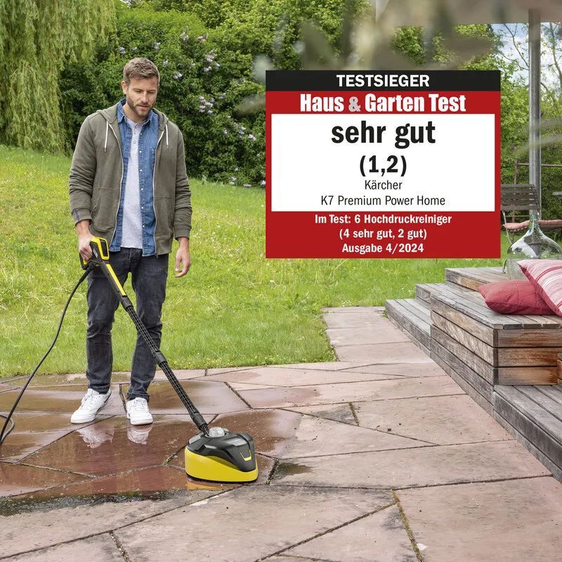 Junger Mann reinigt eine mit Steinplatten geflieste Terrasse mit einem Kärcher Flächenreiniger