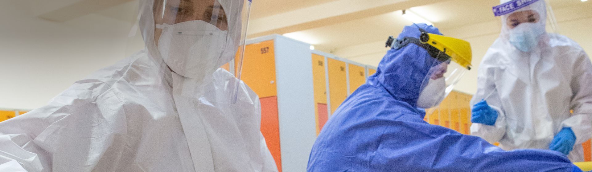 Arbeiterinnen in blauen und weißen Einweg-Schutzanzügen Arbeiterinnen in blauen und weißen Einweg-Schutzanzügen