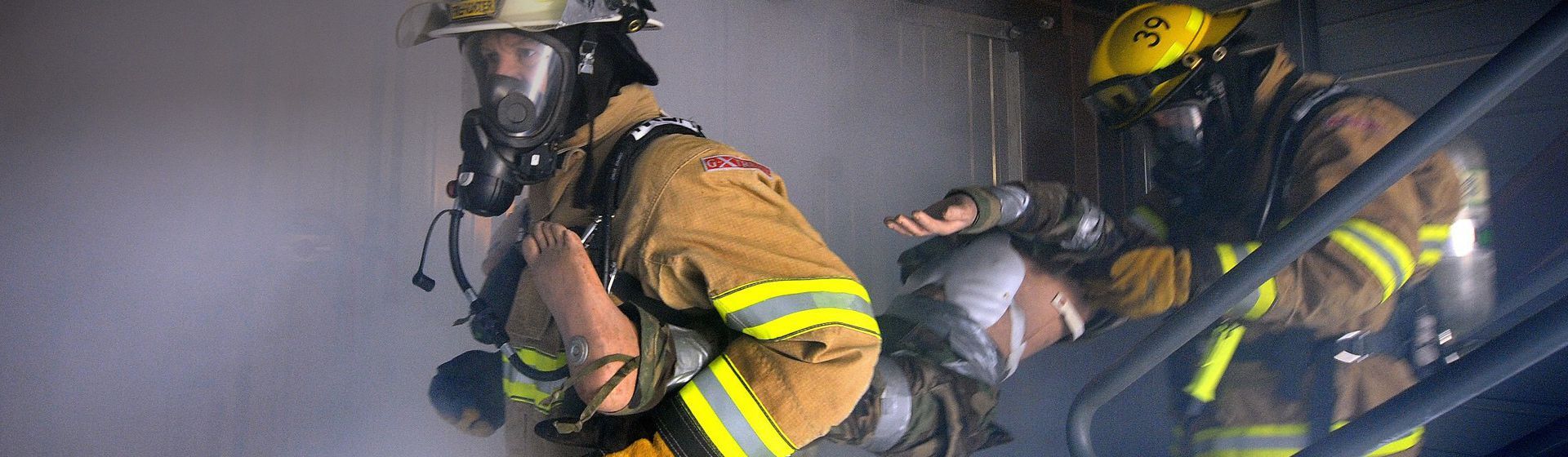 Zwei Feuerwehrmänner in voller Montur bei der Rettung einer Person