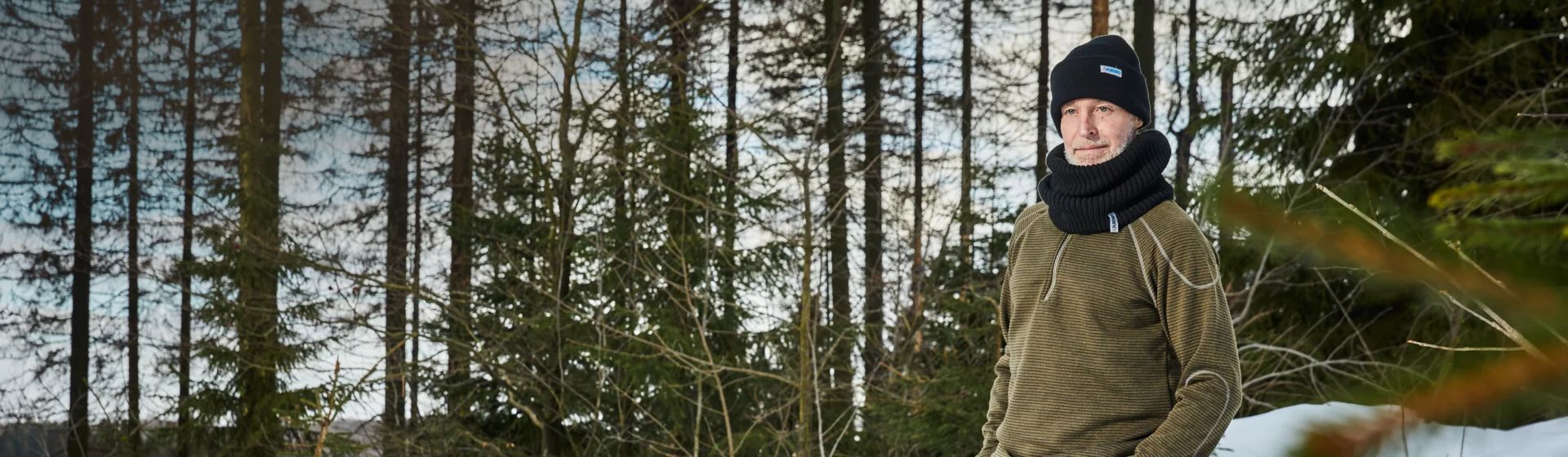 Ein Mann mit schwarzem Schal und schwarzer Wollmütze im winterlichen Wald Ein Mann mit schwarzem Schal und schwarzer Wollmütze im winterlichen Wald