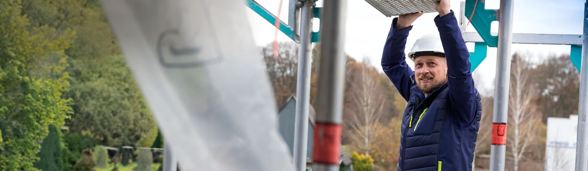 Handwerker auf einem Gerüst  in einer dunkelblauen Softshell Jacke von Planam Handwerker auf einem Gerüst  in einer dunkelblauen Softshell Jacke von Planam