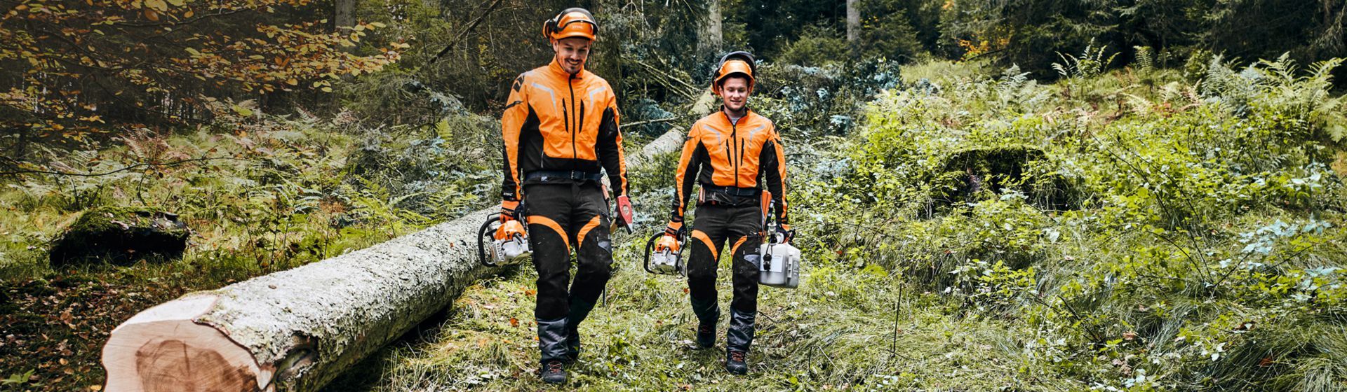 Zwei junge Männer mit Stihl Forstschutzkleidung und Schutzhelm im Wald Zwei junge Männer mit Stihl Forstschutzkleidung und Schutzhelm im Wald