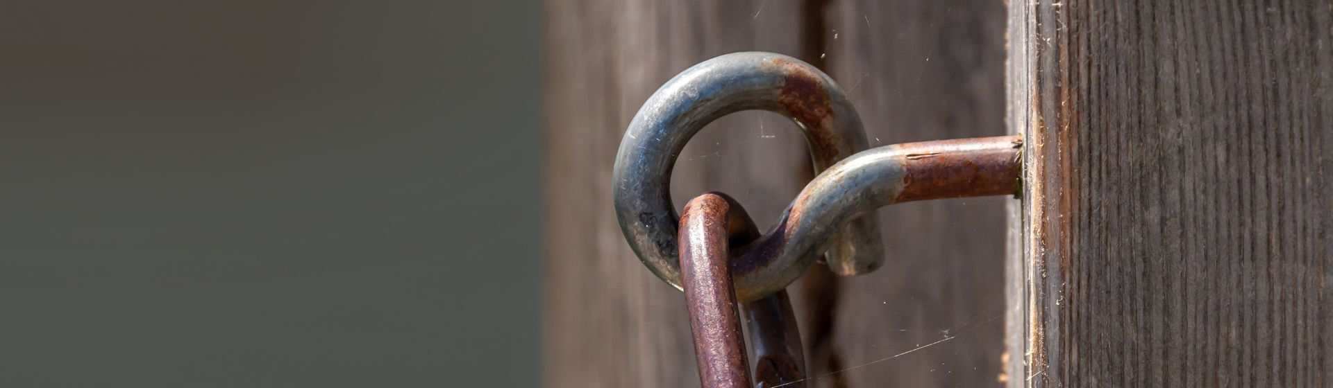 Rostiger Haken in einem Holzpfahl steckend Rostiger Haken in einem Holzpfahl steckend