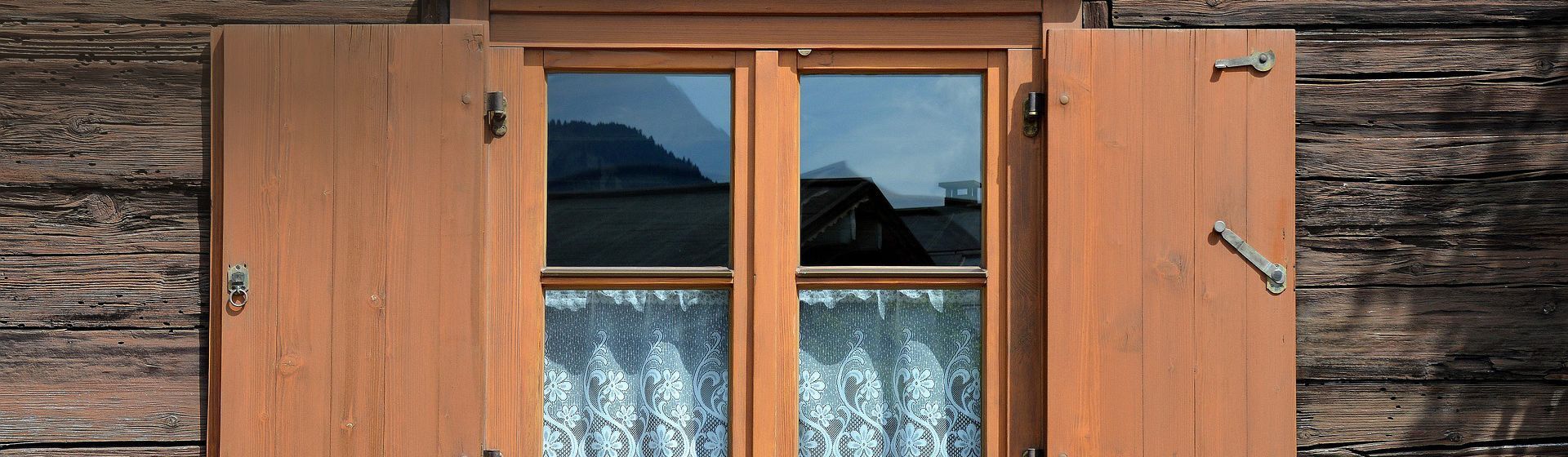 Fensterladen-Feststeller an einem braunen Fensterladen eines Bauernhauses Fensterladen-Feststeller an einem braunen Fensterladen eines Bauernhauses