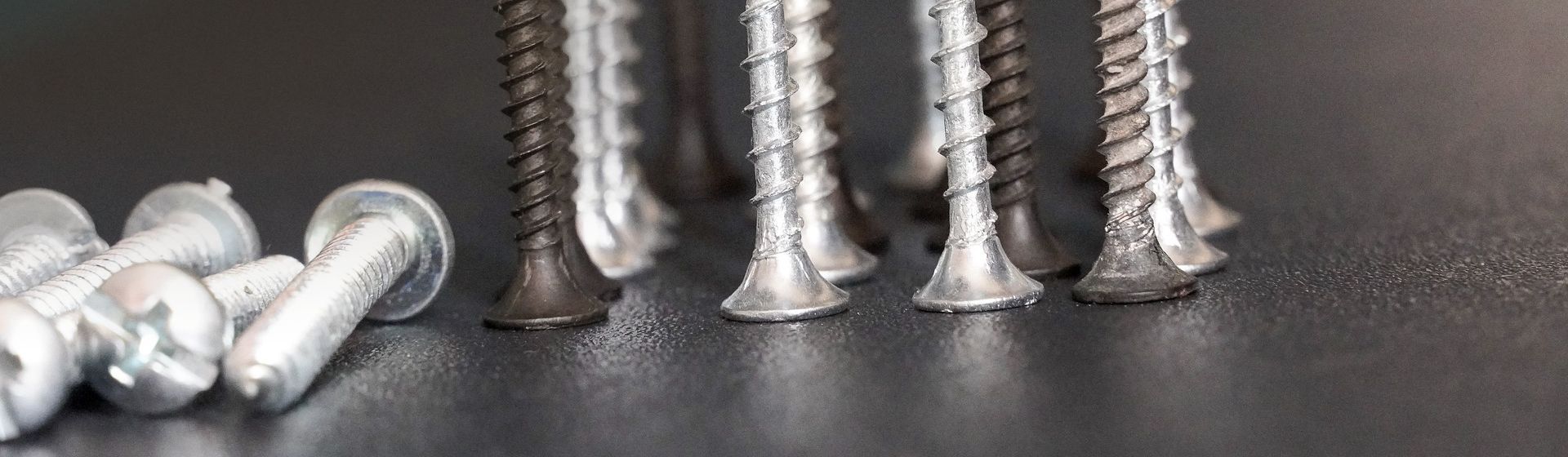 Köpfe verschiedener silberfarbener und schwarzer Schrauben stehend in Nahaufnahme Köpfe verschiedener silberfarbener und schwarzer Schrauben stehend in Nahaufnahme