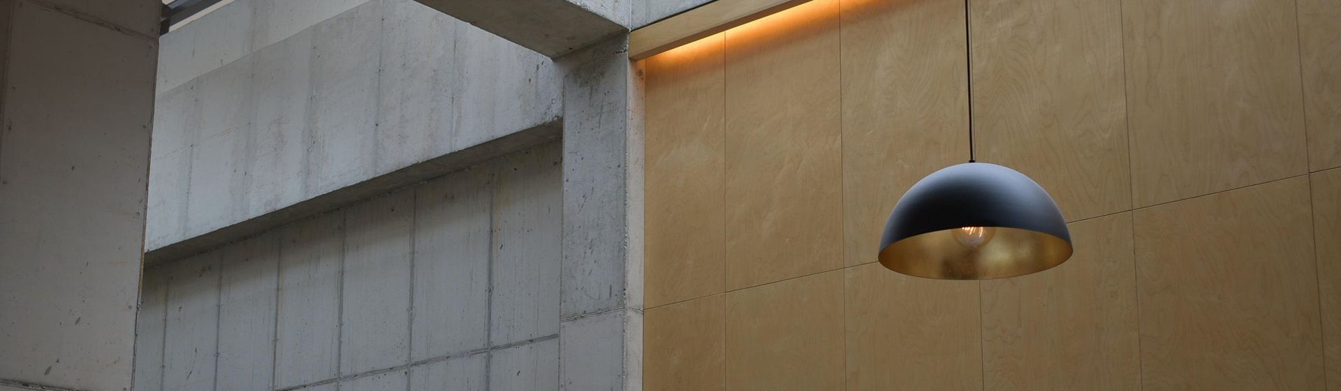 Schwarz-goldene Pendelleuchte in der Eingangshalle eines hohen Gebäudes hängend