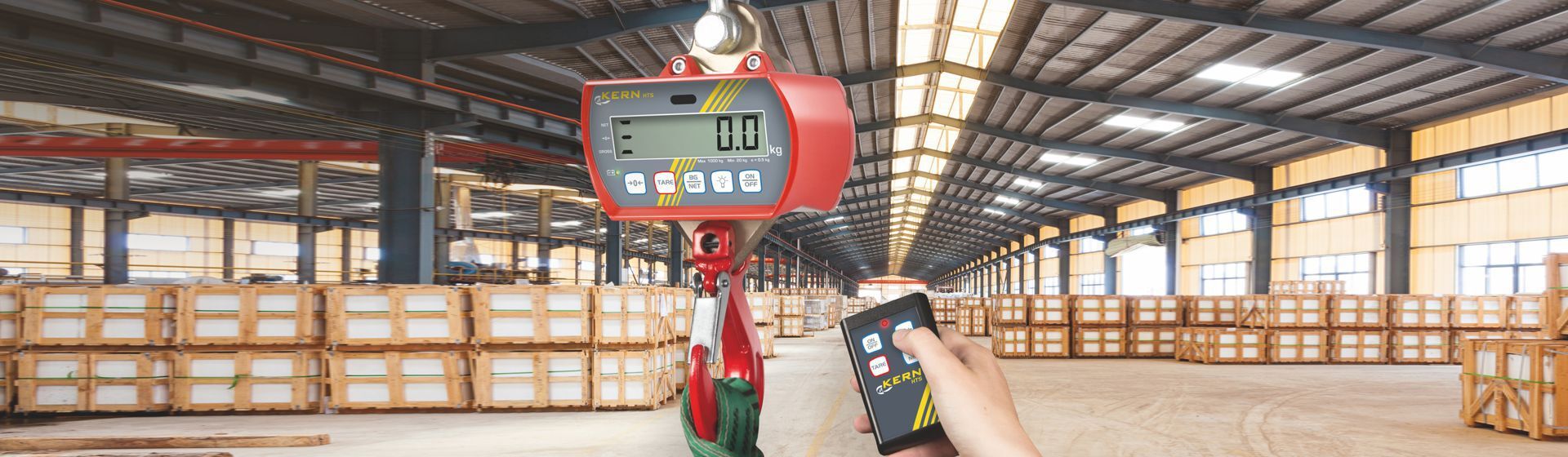 Rote Kern Hängewaage in Nahaufnahme, im Hintergrund eine Lagerhalle Rote Kern Hängewaage in Nahaufnahme, im Hintergrund eine Lagerhalle