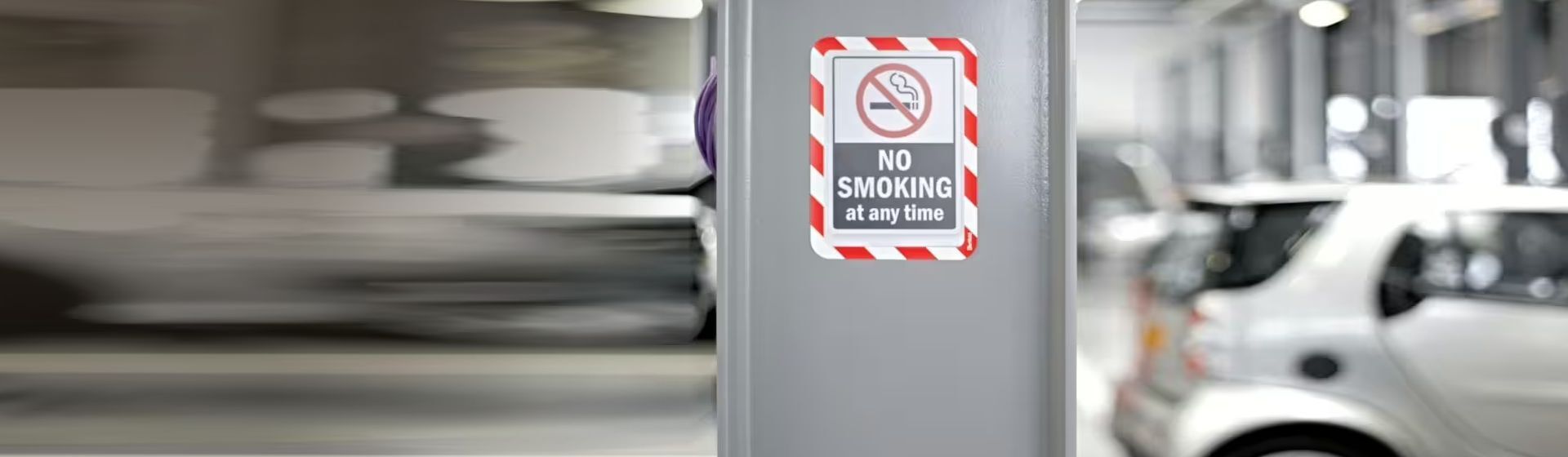Rot-weiß gerahmte Sichttafel mit dem Hinweis "no smoking at any time" an einer grauen Betonsäule montiert Rot-weiß gerahmte Sichttafel mit dem Hinweis "no smoking at any time" an einer grauen Betonsäule montiert