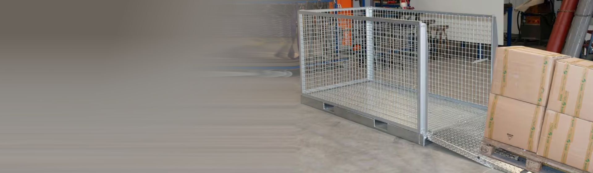 Silberne Gitterbox aus Metall mit einer Beladerampe auf dem Boden eines Lagers stehend Silberne Gitterbox aus Metall mit einer Beladerampe auf dem Boden eines Lagers stehend