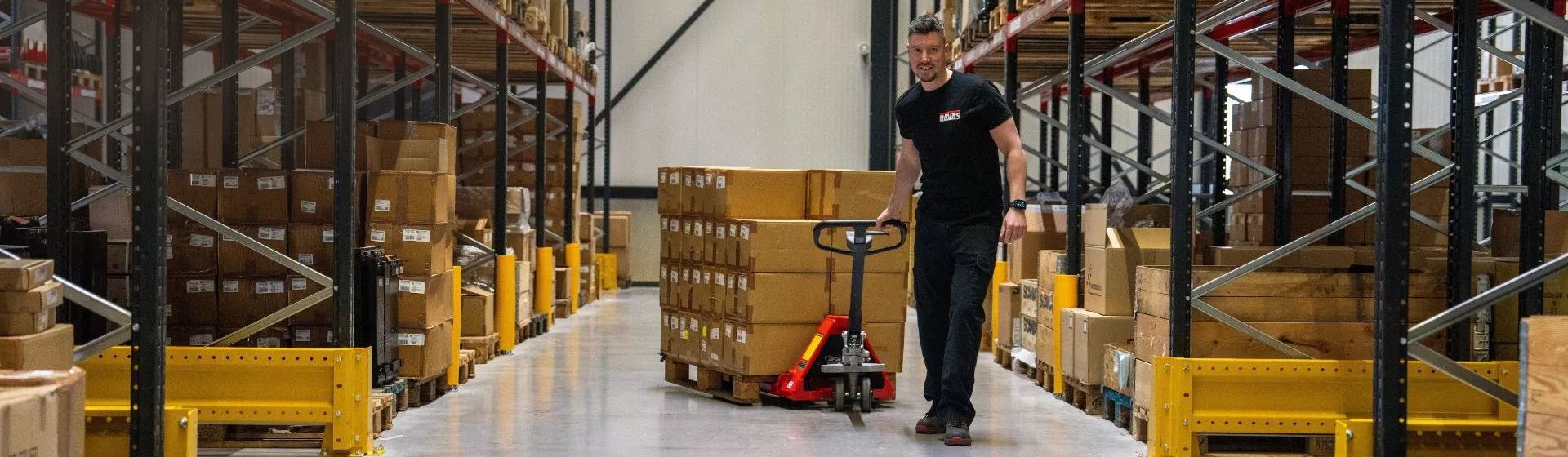 Ravas Hubwagen im Einsatz zum Transportieren einer Palette mit Paketen Ravas Hubwagen im Einsatz zum Transportieren einer Palette mit Paketen