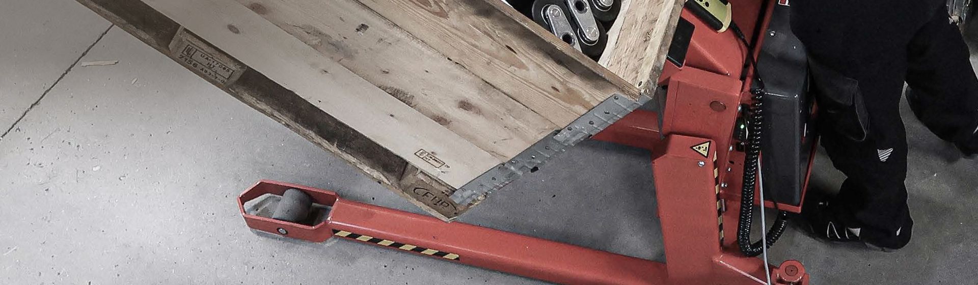 Unterer Teil eines roten Hochhubwagens von Logitrans in Nahaufnahme Unterer Teil eines roten Hochhubwagens von Logitrans in Nahaufnahme