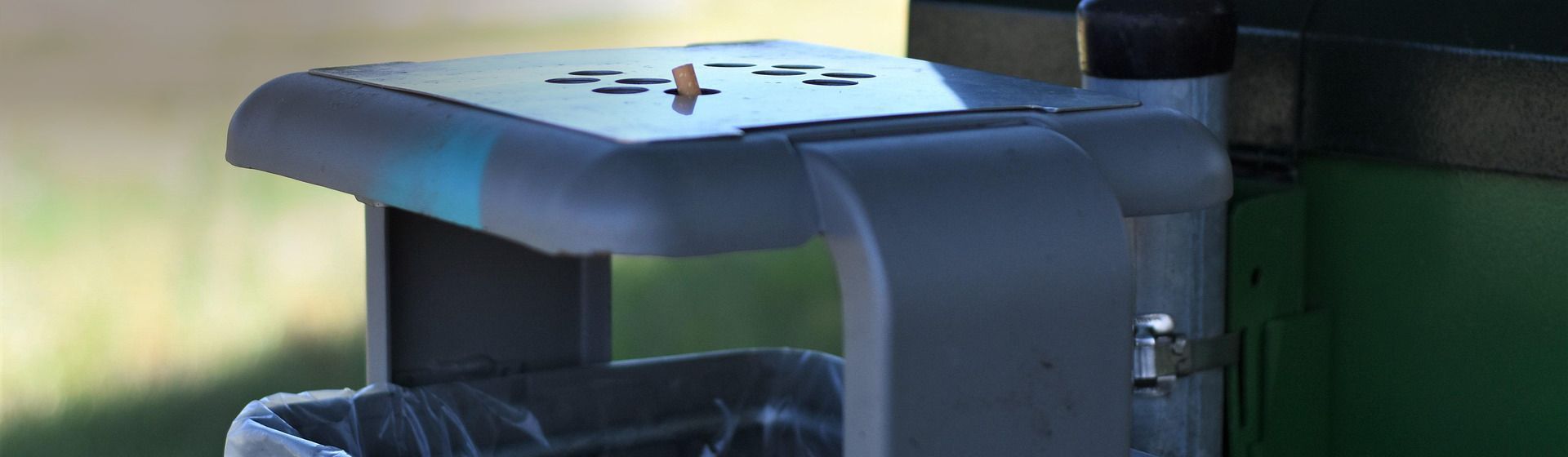 Grauer Abfalleimer mit Ascher, in dem eine ausgedrückte Zigarette steckt Grauer Abfalleimer mit Ascher, in dem eine ausgedrückte Zigarette steckt