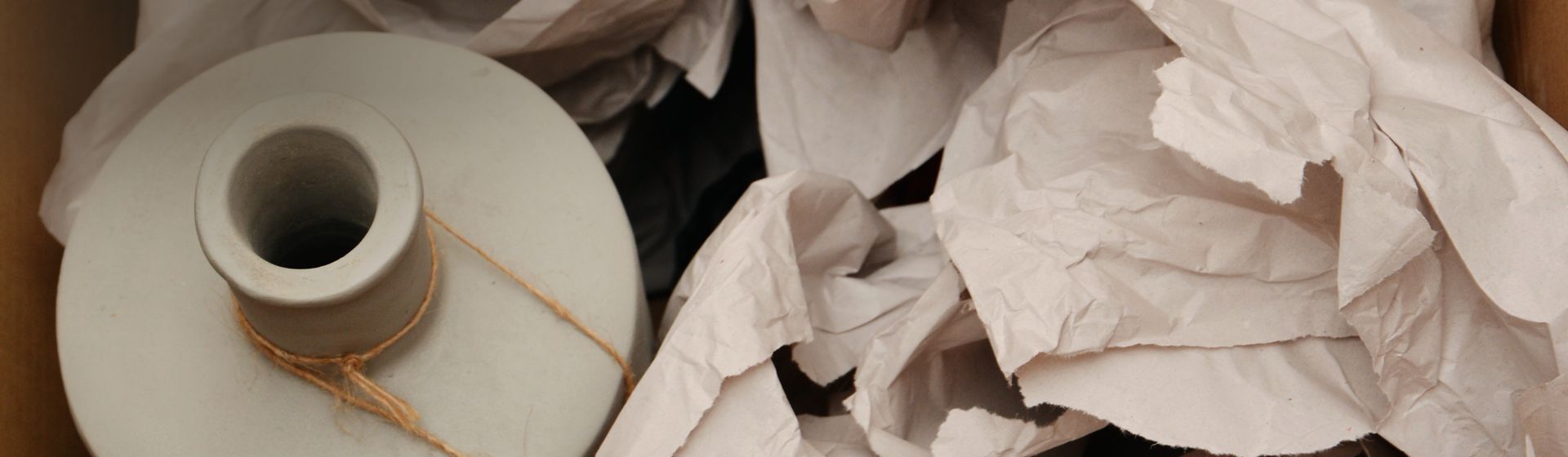 Packpapier in einem Karton um eine Vase herum verteilt Packpapier in einem Karton um eine Vase herum verteilt