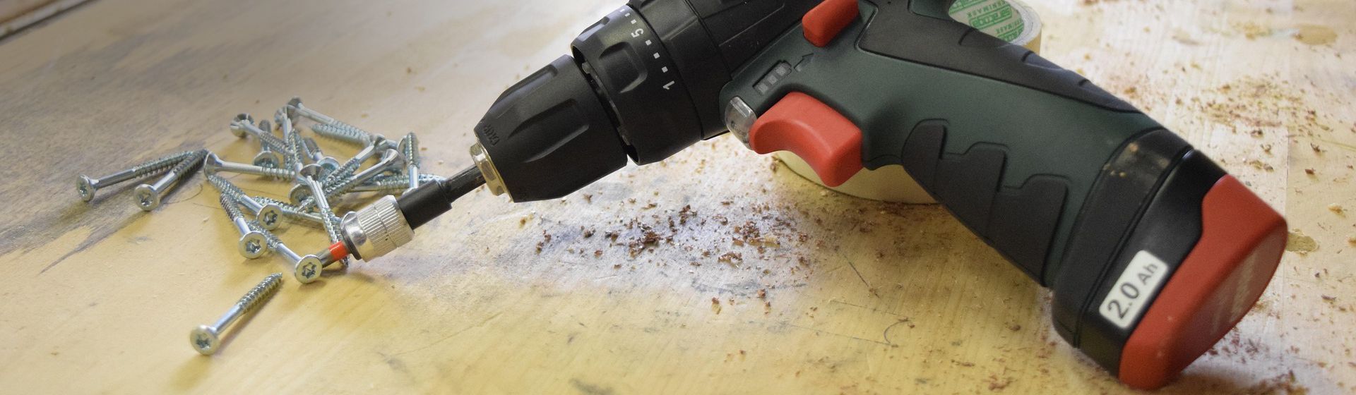 Metabo Bohrmaschine auf einer Werkbank neben Schrauben liegend Metabo Bohrmaschine auf einer Werkbank neben Schrauben liegend