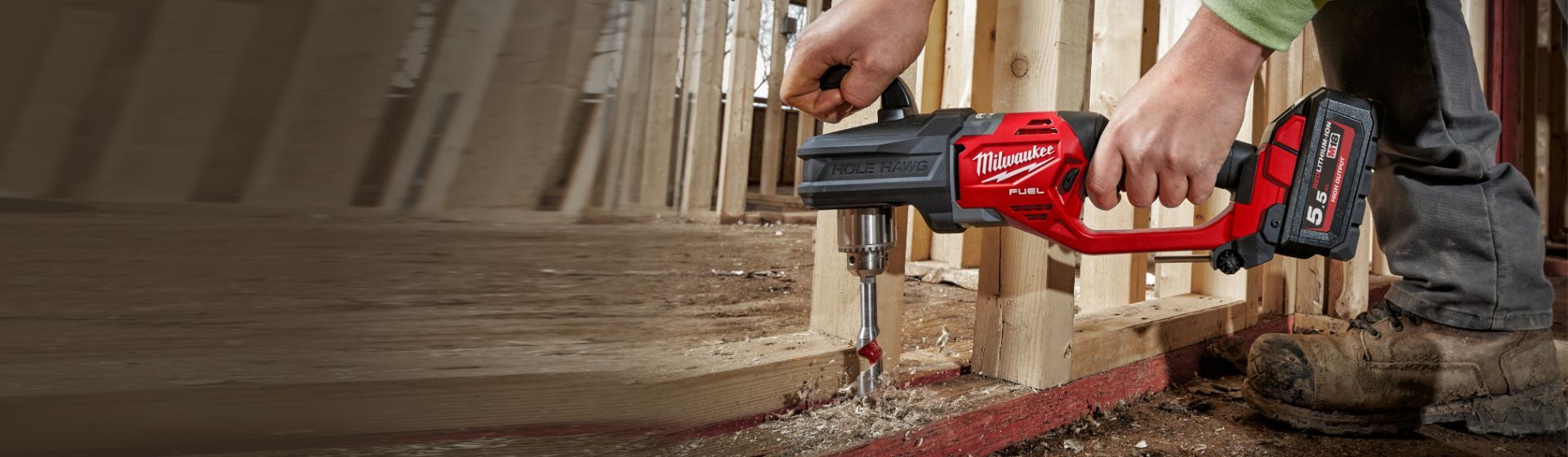 Milwaukee Winkelbohrmaschine beim Bohren eines Lochs in die Holzstruktur am Boden Milwaukee Winkelbohrmaschine beim Bohren eines Lochs in die Holzstruktur am Boden