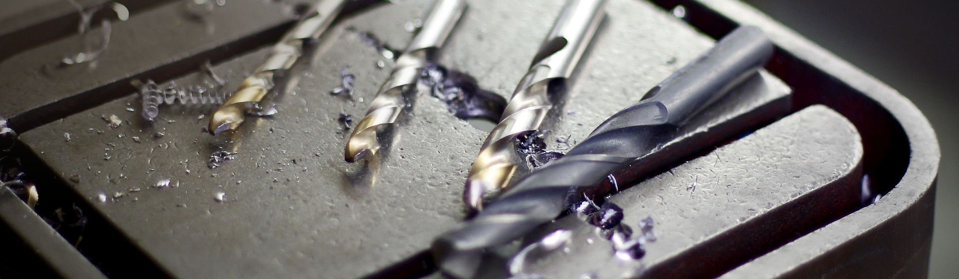 Vier Bohrer auf einer dunklen Metalloberfläche liegend Vier Bohrer auf einer dunklen Metalloberfläche liegend