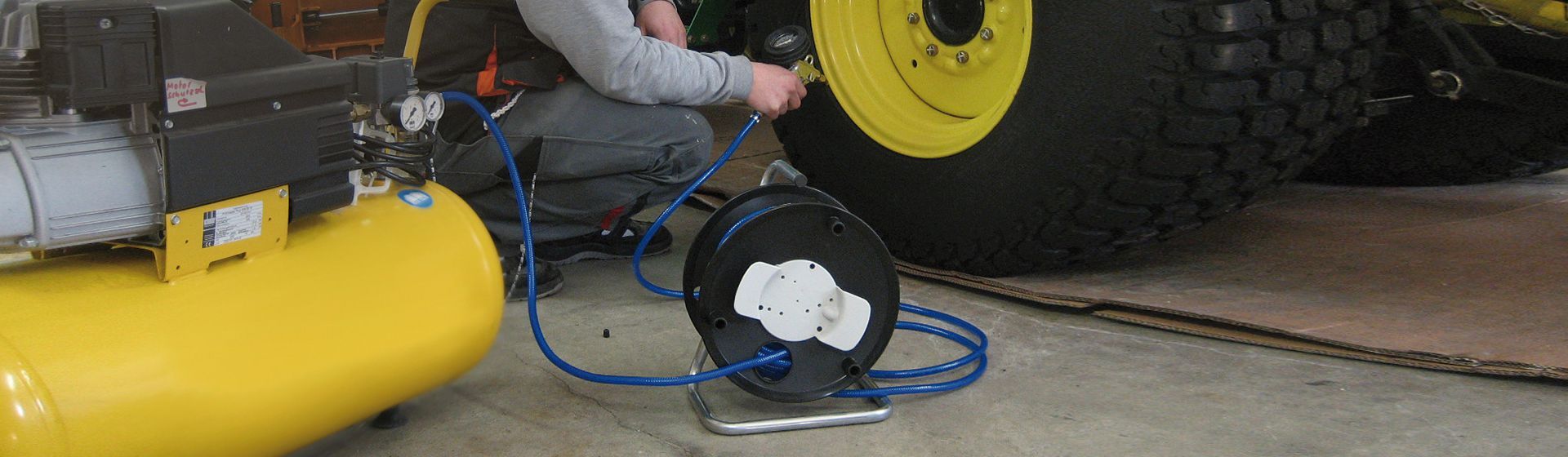 Brennenstuhl Druckluft Kabeltrommel in schwarz mit ausgerolltem blauen Kabel beim Befüllen eines Nutzfahrzeuge-Reifens mit Druckluft