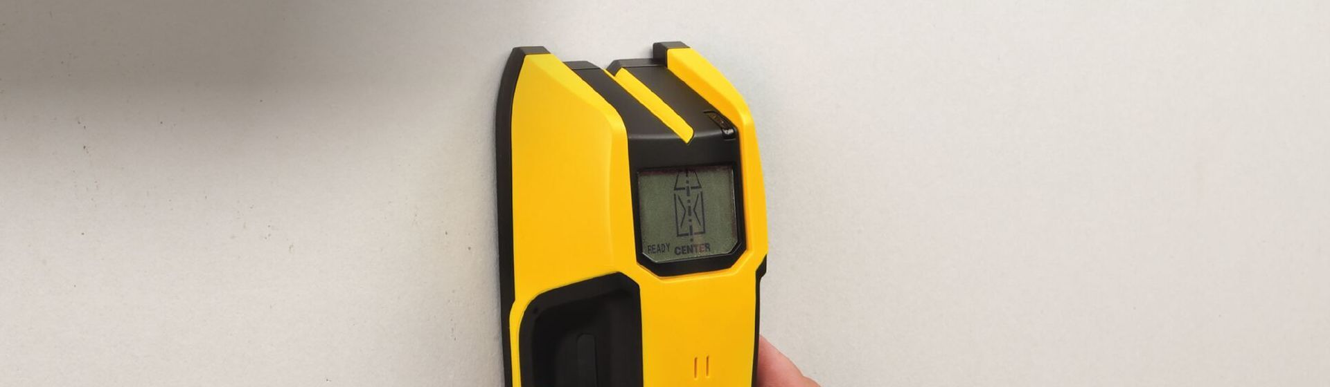Materialdetektor von Stanley im Einsatz bei Messungen an einer Wand Materialdetektor von Stanley im Einsatz bei Messungen an einer Wand