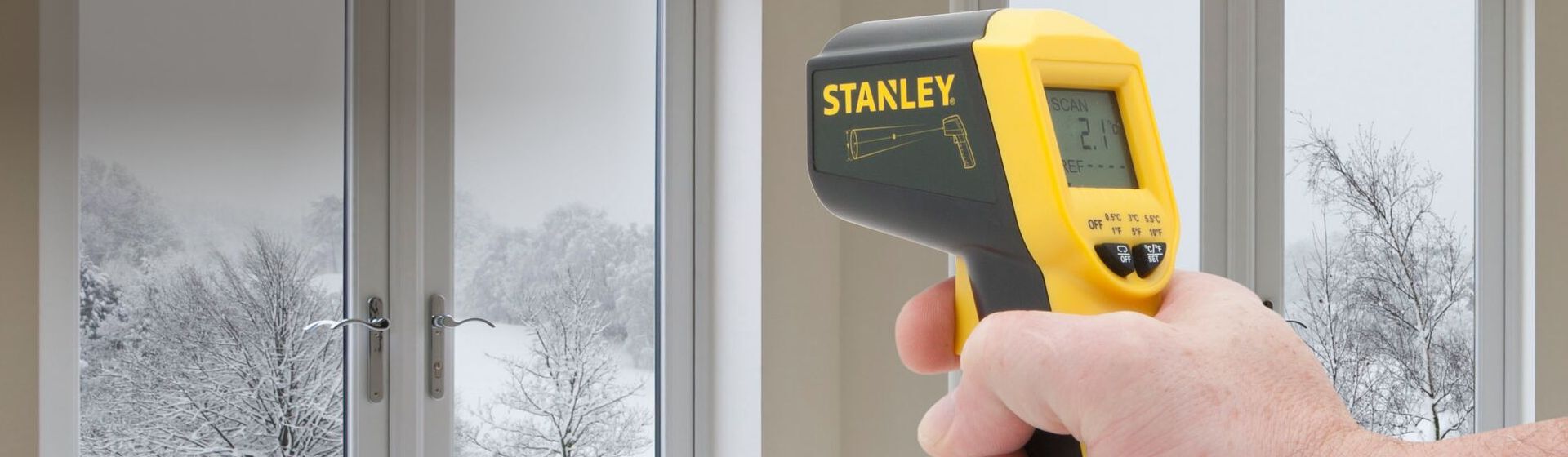 Digitales Infrarot Thermometer von Stanley bei der Temperaturmessung an einer Fensterfront Digitales Infrarot Thermometer von Stanley bei der Temperaturmessung an einer Fensterfront
