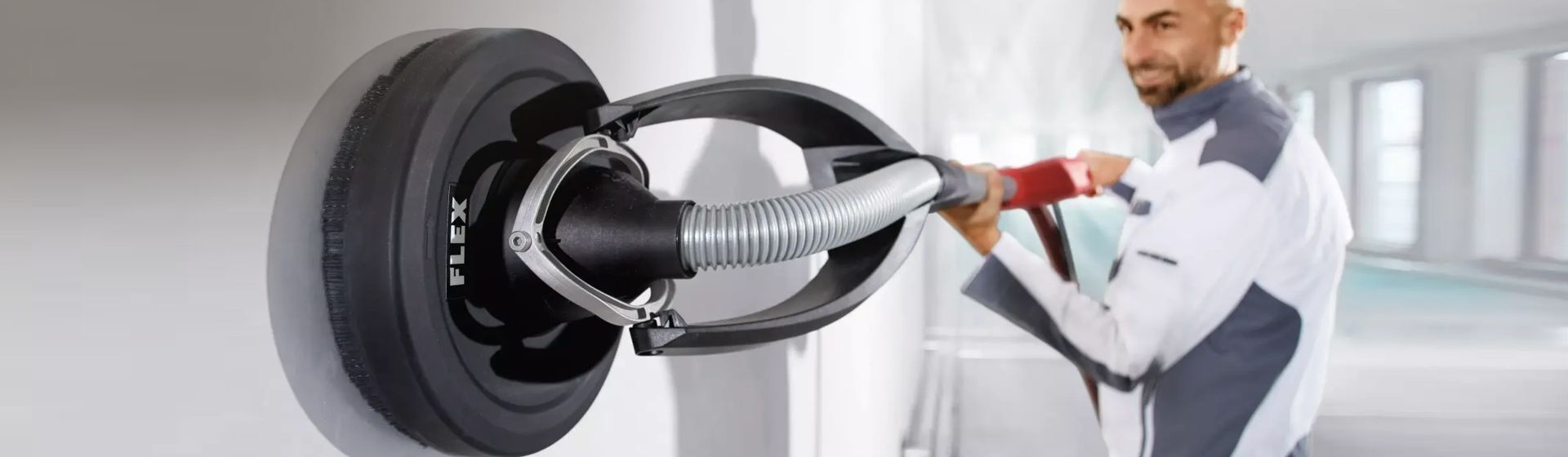 Handwerker beim Bearbeiten einer weißen Wand mit einer Flex Sanierungsgiraffe Handwerker beim Bearbeiten einer weißen Wand mit einer Flex Sanierungsgiraffe