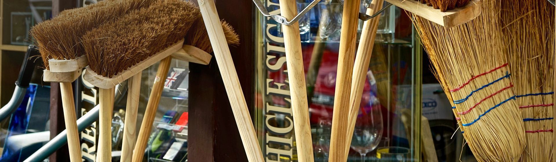 Mehrere Holzbesen zusammen in einem Verkaufsständer vor einem Ladengeschäft Mehrere Holzbesen zusammen in einem Verkaufsständer vor einem Ladengeschäft