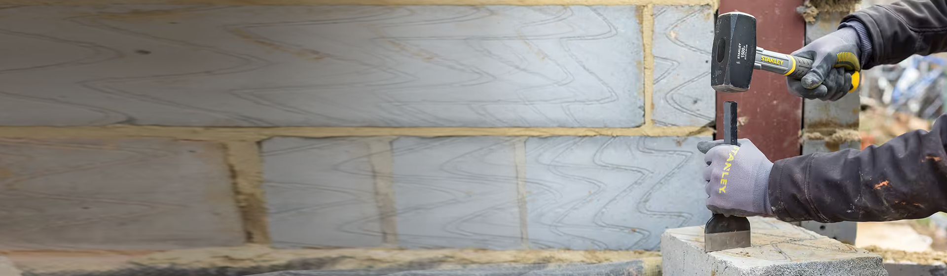 Handwerker bearbeitet einen Stein mit Hilfe eines Meißels und eines Fäustels Handwerker bearbeitet einen Stein mit Hilfe eines Meißels und eines Fäustels