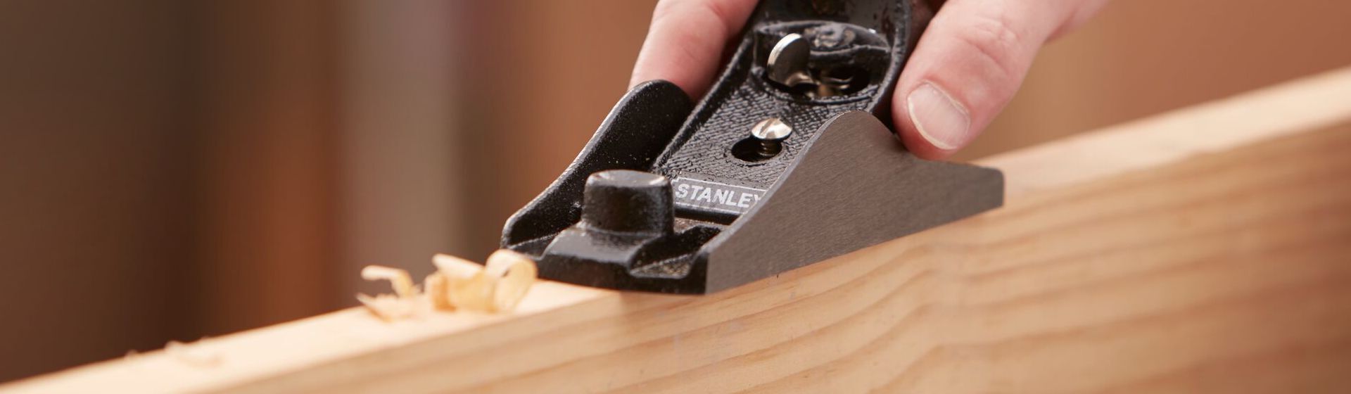 Schwarzer Einhandhobel von Stanley beim Bearbeiten einer Holzlatte