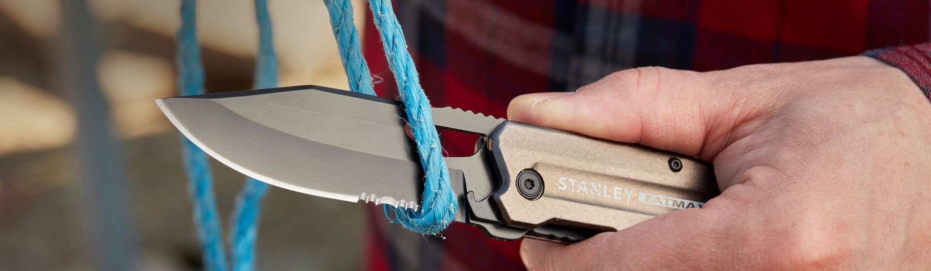 Silberfarbenes Taschenmesser von Stanley beim Durchtrennen eines blauen Stricks Silberfarbenes Taschenmesser von Stanley beim Durchtrennen eines blauen Stricks