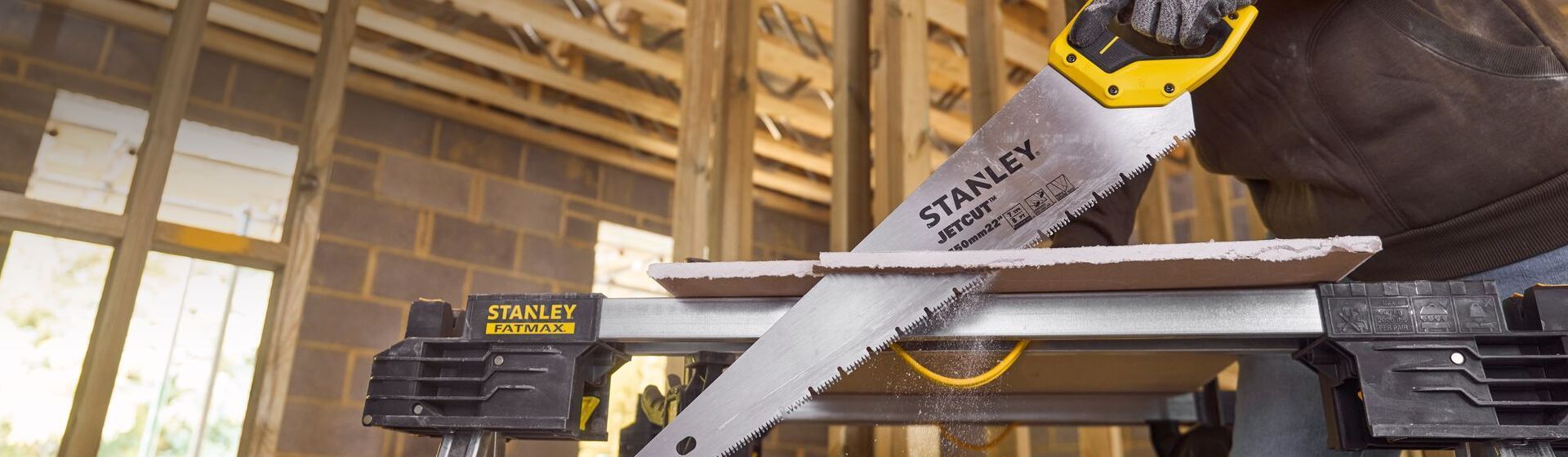 Mann sägt mit einer Dämmstoffsäge von Stanley eine Dämmstoffplatte Mann sägt mit einer Dämmstoffsäge von Stanley eine Dämmstoffplatte