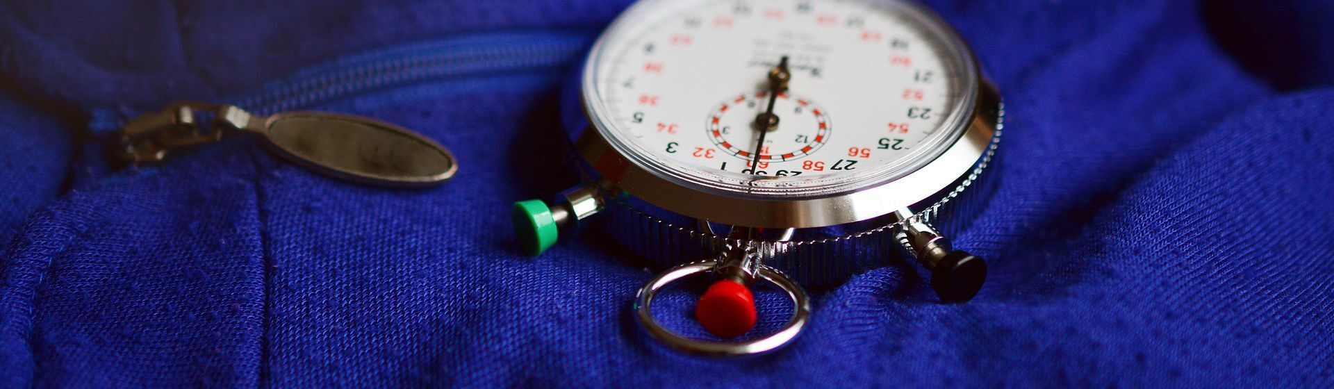 Runde manuelle Stoppuhr auf einem blauen Arbeitsoverall liegend Runde manuelle Stoppuhr auf einem blauen Arbeitsoverall liegend