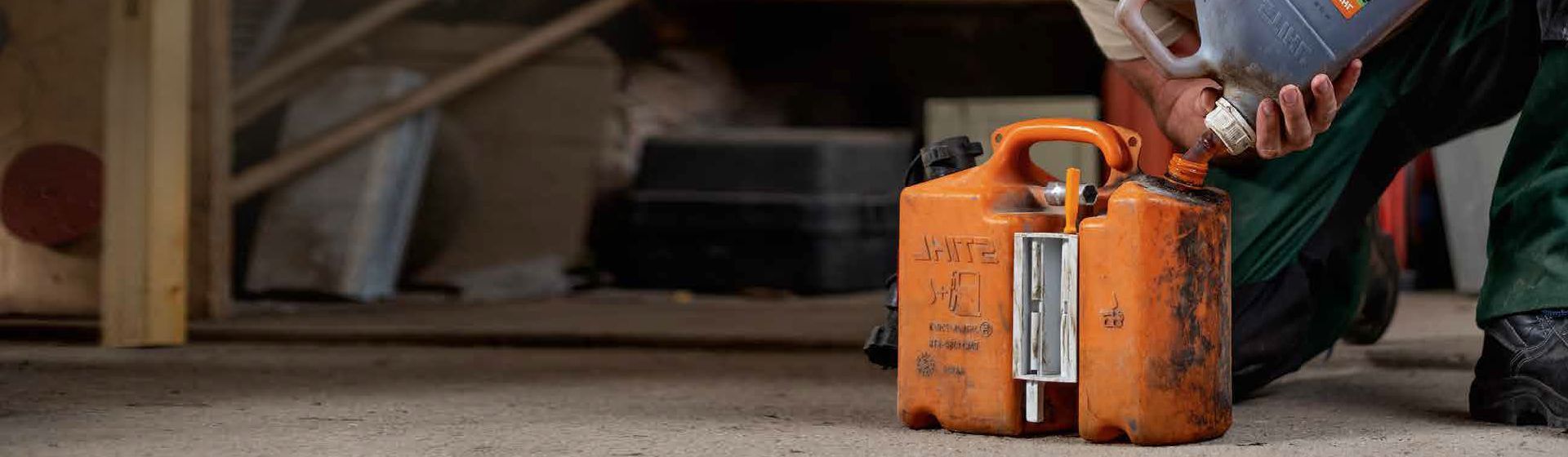 Stihl Benzinkanister auf dem Boden stehend wird gerade befüllt Stihl Benzinkanister auf dem Boden stehend wird gerade befüllt